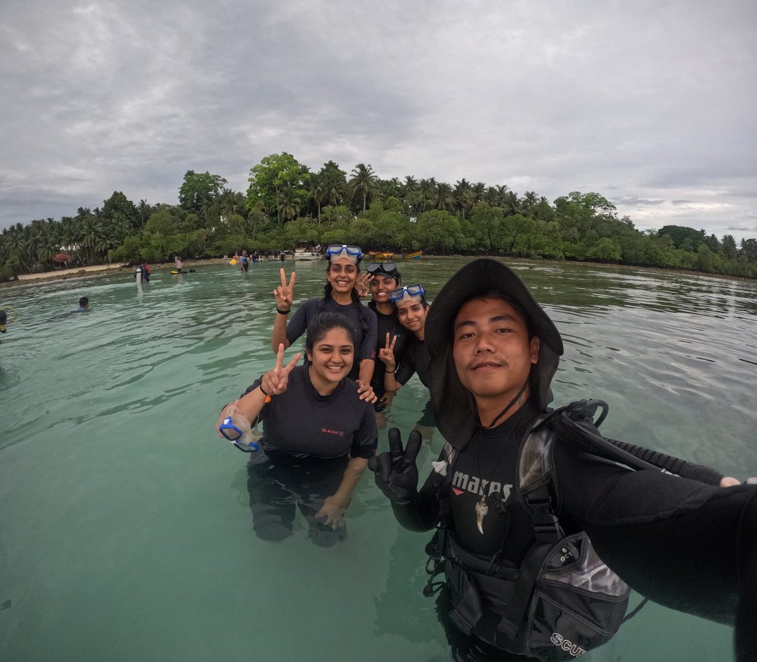 Happy Scuba India divers giving peace signs in shallow water off a Havelock beach