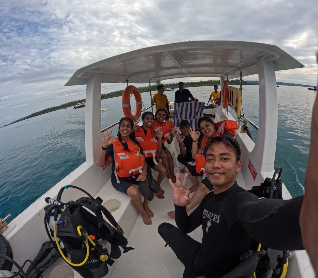 Divers in life jackets on the Scuba India boat giving OK signals after a dive